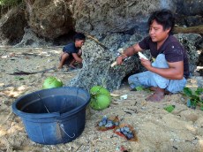 Sharing coconut and grilled shellfish on the beach in Bunaken, Sulawesi
